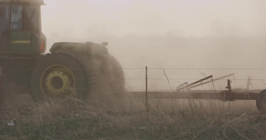A tractor is working the field of a farm