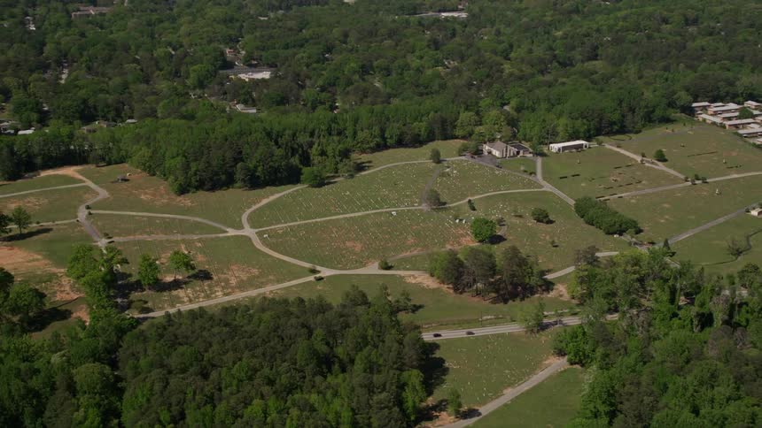 Aerial footage flying by a cemetery surrounded by trees in Atlanta Georgia on a sunny day