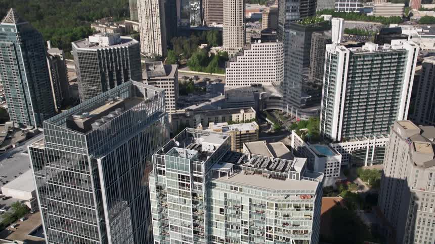 Approaching and tilting down on a modern office building amongst a metropolis of skyscrapers in Buckhead Georgia