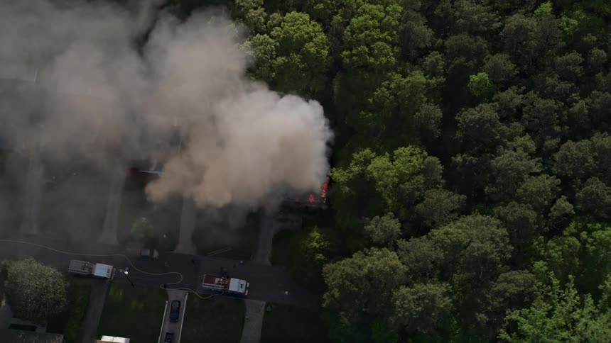 Aerial footage of a burning home in West Atlanta with smoke and flames visible as the camera approaches and tilts to a birds eye view
