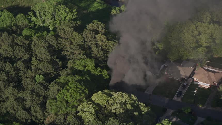 Aerial footage shows dark smoke rising from a house fire in a neighborhood surrounded by a forest in West Atlanta Georgia