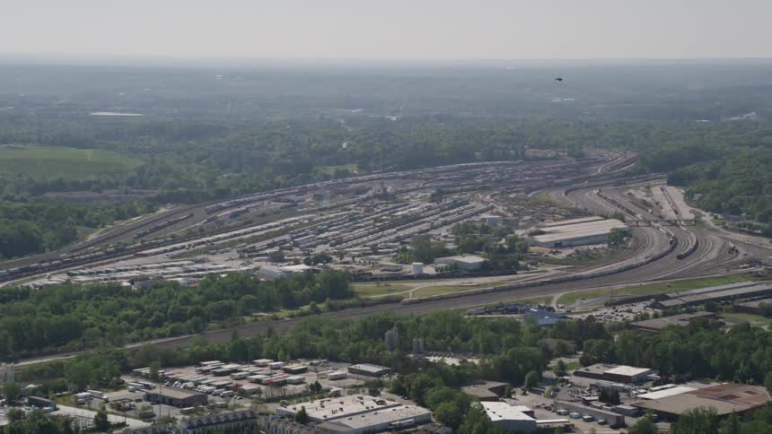 Approaching aerial footage of a train yard in hazy Atlanta Georgia during the summer