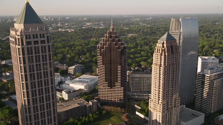 Approaching Midtown Atlanta skyscrapers and revealing Promenade II amidst the modern high-rises and towers during sunset