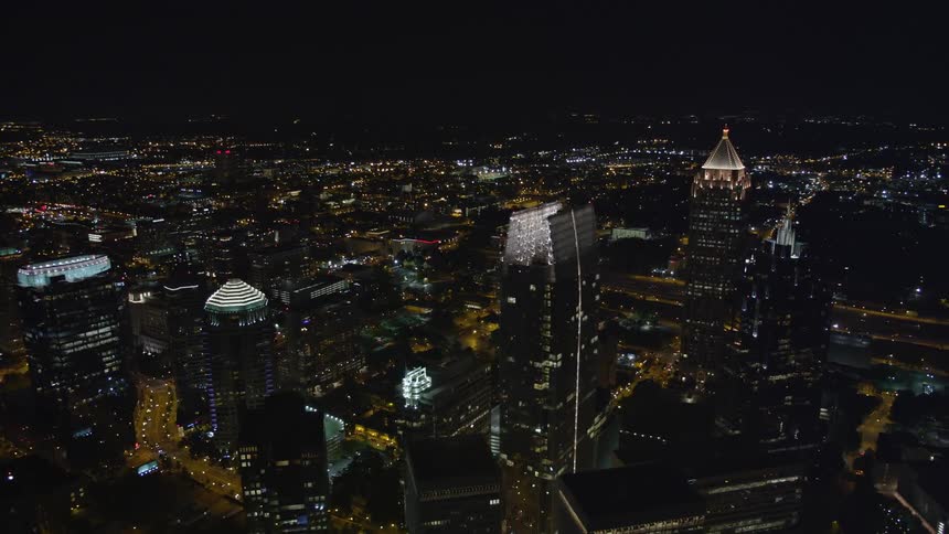 A nighttime aerial view flying by towering skyscrapers in the city of Atlanta Georgia