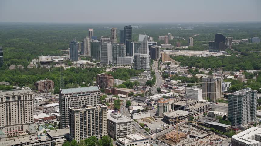 A stunning aerial view of Buckhead Georgia with Peachtree Road in focus followed by a gradual tilt up to a panoramic view of towering buildings and high-rises in the city