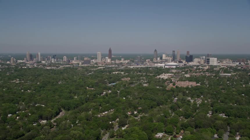 Aerial footage of Midtown and Downtown Atlanta taken during the day showing the cityscape and skyscrapers from a side view in West Atlanta GA