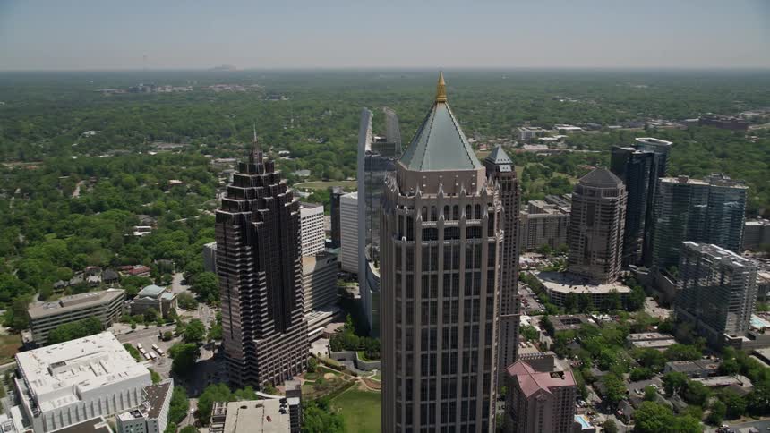 A stunning aerial view of the skyscrapers in downtown Midtown Atlanta Georgia surrounded by lush trees and green space during a sunny Summer day