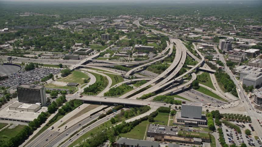 Aerial footage of a freeway interchange orbiting Downtown Atlanta during a sunny summer day with light traffic