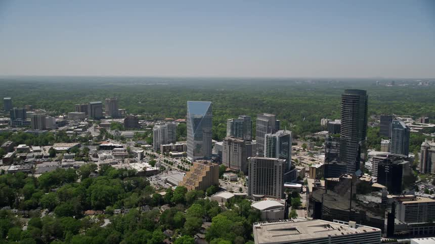 Approaching Terminus Atlanta by aerial view this footage tilts down to a birds eye shot of Buckhead Georgia showcasing the modern glass buildings and skyscrapers of the metropolitan area