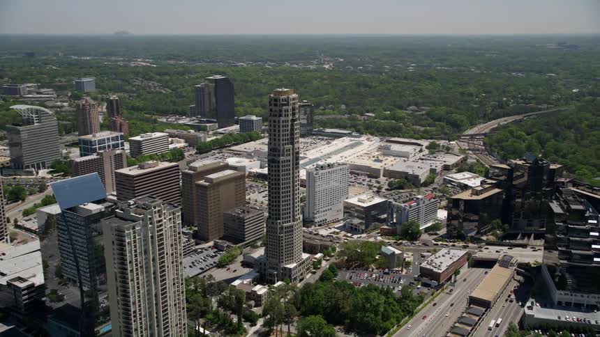 Flying by The Mansion in Buckhead Georgia this aerial footage reveals the sleek modern tower of 3344 Peachtree amidst the metropolis of Atlanta on a sunny day