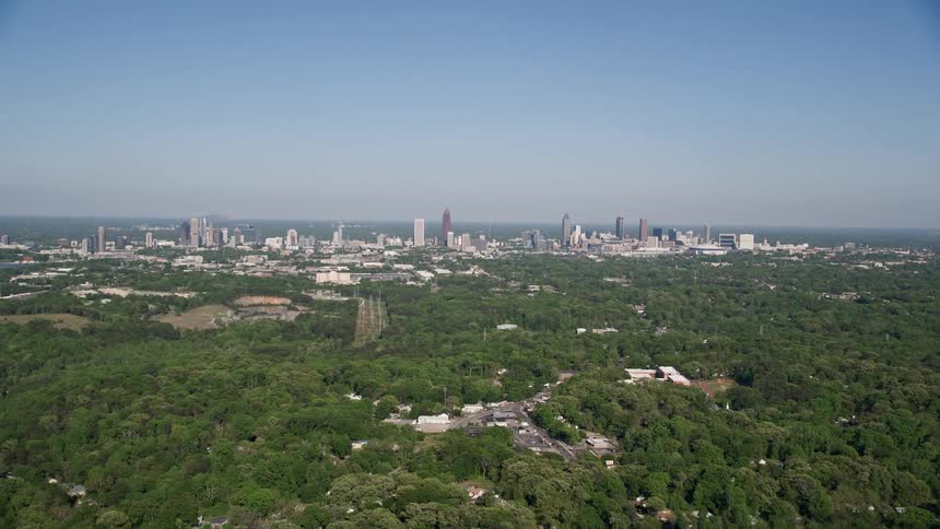 Aerial footage of Atlantas forests Midtown and Downtown featuring its skyline with tall and stunning skyscrapers on a sunny day
