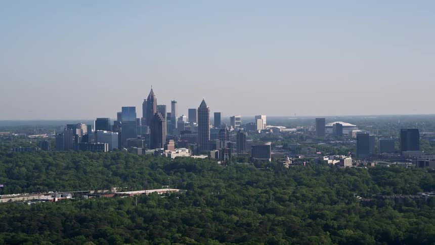 Aerial view of Midtown Atlanta skyscrapers rising above lush trees captured on a sunny summer day