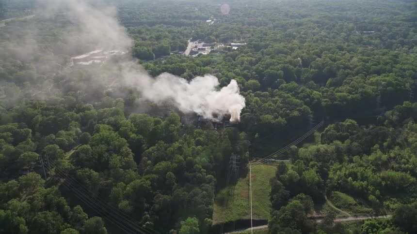Aerial footage of a house fire in West Atlanta as the drone moves away from smoke and approaches the burning house from a birds eye view