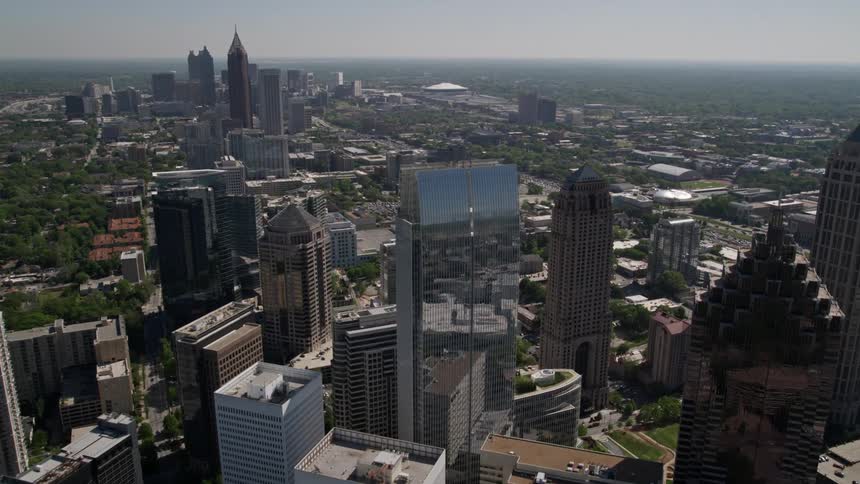 Approaching 1180 Peachtree skyscraper this aerial footage tilts to a stunning birds eye view of Midtown Atlantas modern high-rises during a sunny summer day