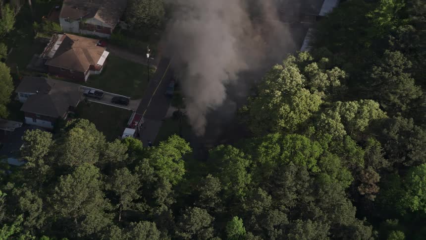Aerial footage of a West Atlanta home on fire with smoke rising into the sunny sky