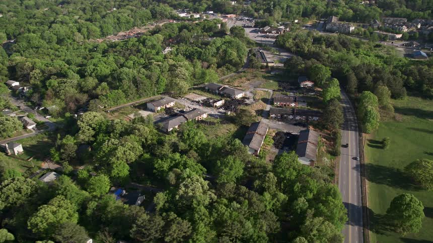 Aerial footage shows abandoned buildings obscured by trees in West Atlanta during daytime