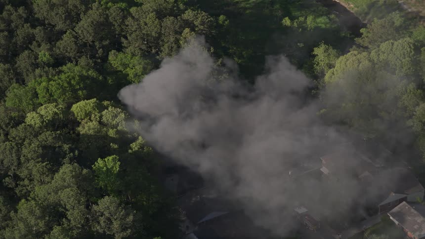 Aerial footage of a house fire in West Atlanta Georgia with smoke billowing up as fire trucks and emergency services respond