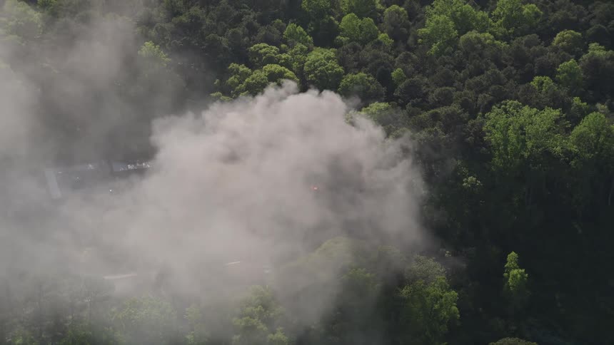 Aerial footage orbits above a burning residence capturing billowing smoke in West Atlanta Georgia
