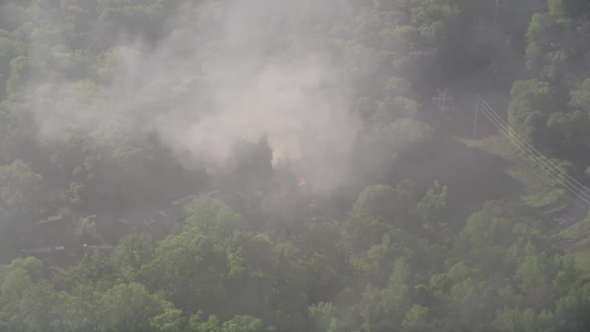 Aerial footage of a house on fire in West Atlanta with smoke rising and emergency services at the scene
