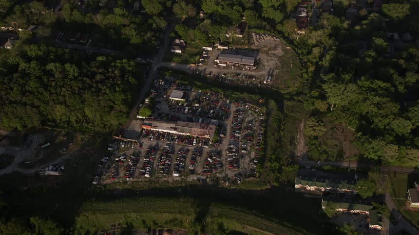 Aerial footage of a junkyard in West Atlanta Georgia during day time tilting down towards abandoned vehicles