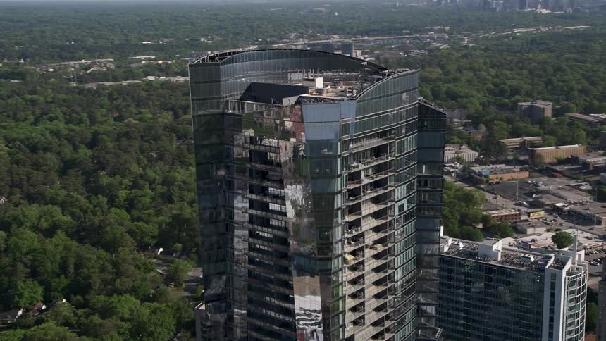 Aerial footage approaching and orbiting the reflective 3344 Peachtree skyscraper in Buckhead Georgia on a sunny summer day