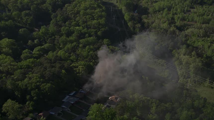 Aerial footage shows smoke rising from a house fire in a wooded area of West Atlanta