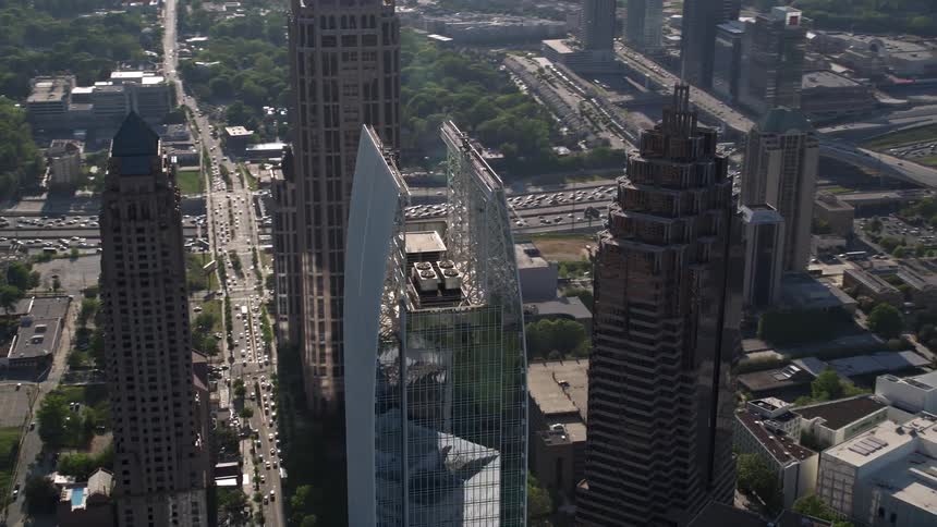 Aerial footage orbiting the 1180 Peachtree skyscraper revealing a sunny midtown Atlanta with other skyscrapers in sight during daytime