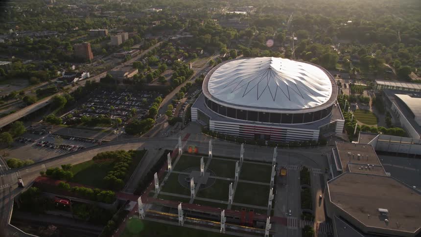 Aerial footage of traffic moving on streets as the camera flies by the Georgia Dome in Atlanta Georgia during daytime