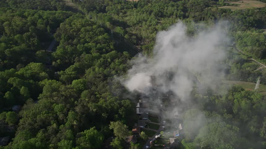 Aerial footage captures thick smoke rising from a house fire in a forested neighborhood of West Atlanta