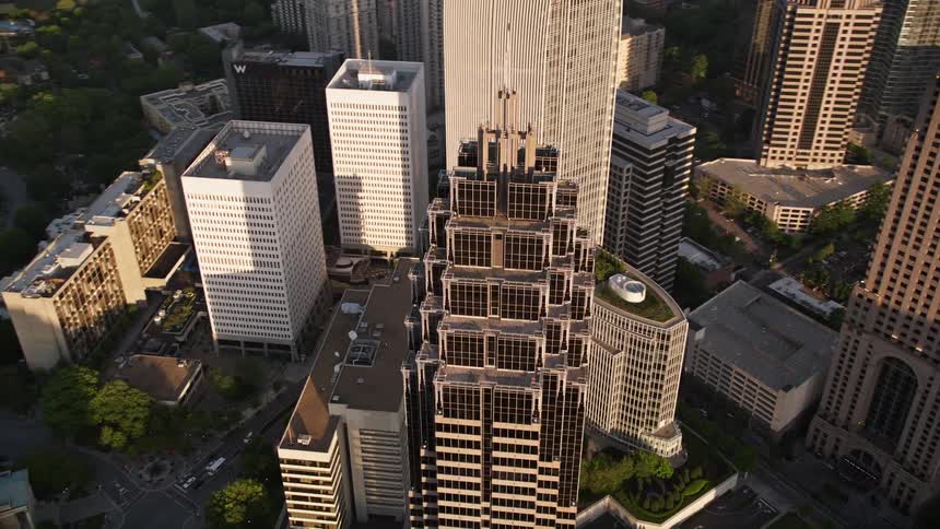 An aerial view approaching and orbiting Atlantas Promenade II a modern high-rise building located in Midtown during daytime or sunset