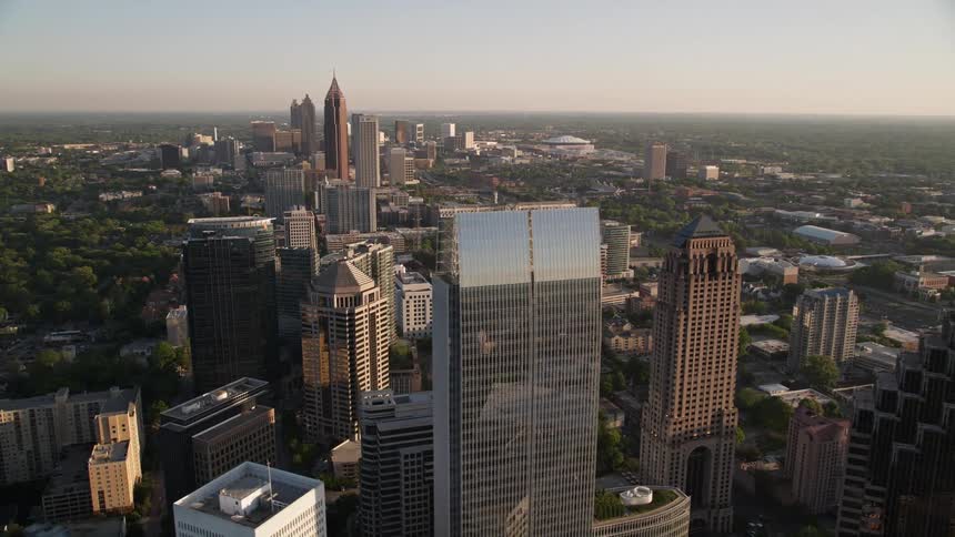 This aerial footage approaches One Atlantic Center and orbits around it revealing more of Midtown Atlanta with hazy sunset lighting