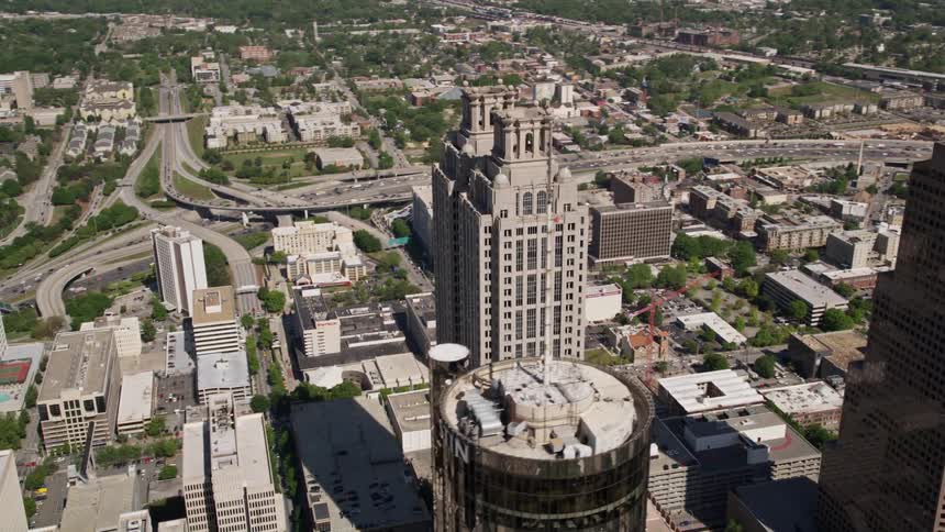 An aerial view over Downtown Atlanta orbiting 191 Peachtree Tower on a sunny day