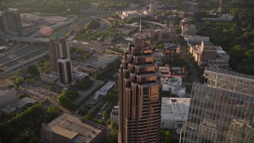 Approaching and orbiting the top of Promenade II this aerial footage showcases the modern high-rise buildings and bustling cityscape of Midtown Atlanta during sunset