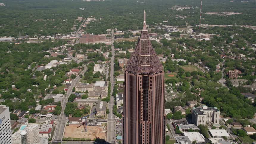 Bank of America Plaza in Midtown Atlanta Georgia is approached and orbited in aerial footage showcasing the sunny summertime metropolis and its towering skyscrapers