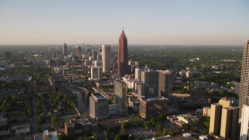 Aerial flyby of Downtown Atlanta skyscrapers to approach Midtown buildings during sunset