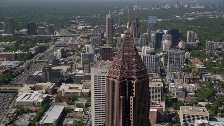 Approaching Bank of America Plaza in Midtown Atlanta the aerial footage tilts to a birds eye view of the high rise building amongst other skyscrapers