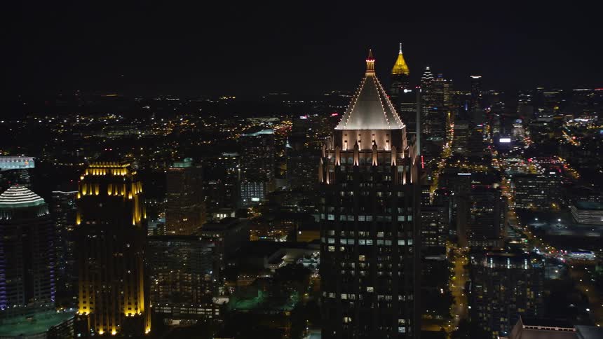 A stunning aerial flyby and orbit of the skyscrapers around One Atlantic Center in Midtown Atlanta Georgia at night showcasing the citys impressive metropolis and towering buildings