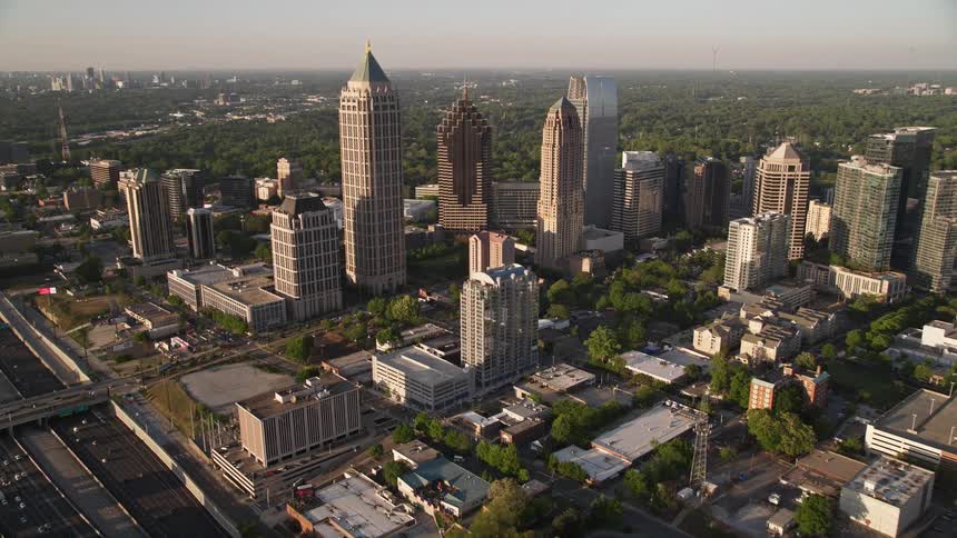 Approaching and circling One Atlantic Center from an aerial view to reveal the modern buildings and skyscrapers of Midtown Atlanta during sunset