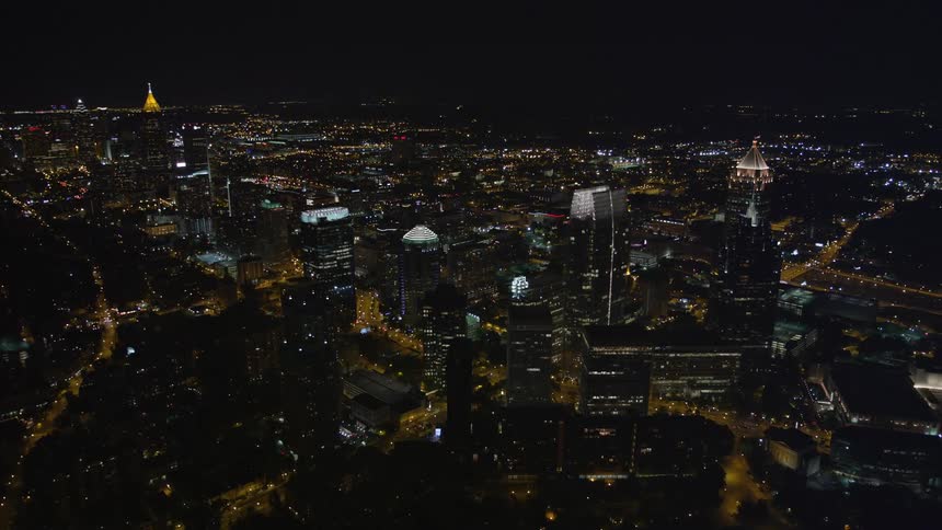 Aerial approach and tilt to birds eye view footage showcasing the stunning lights of the tall skyscrapers- 1180 Peachtree and GLG Grand- overlooking the city of Atlantas metropolitan area at night