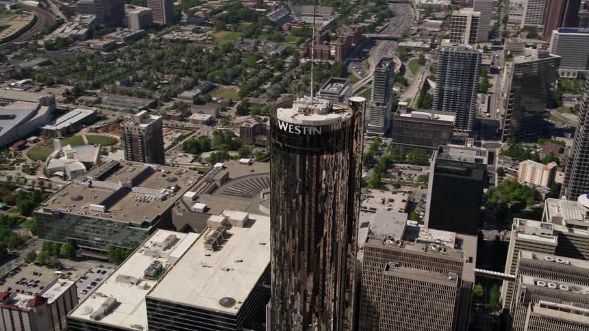 An aerial view of the Westin Peachtree Plaza Hotel in downtown Atlanta Georgia surrounded by other buildings during a sunny summer day