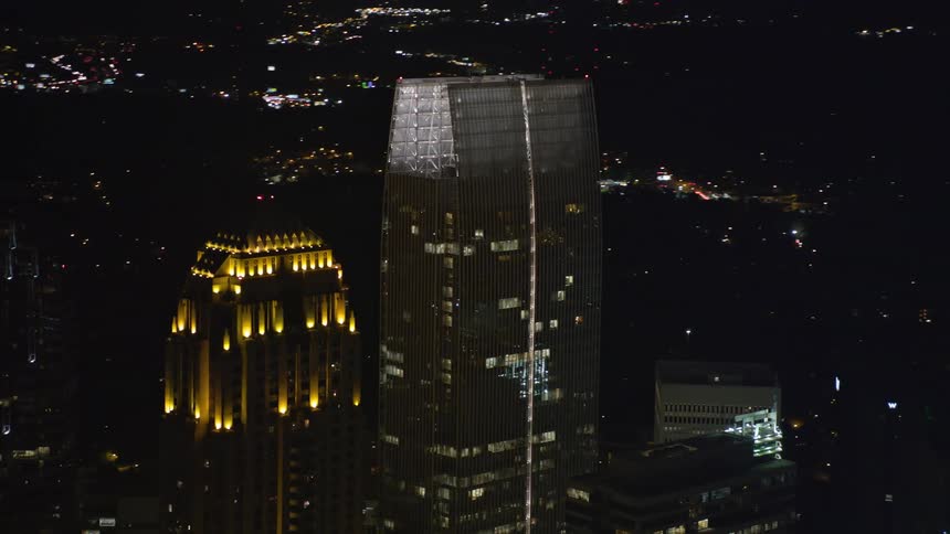 A nighttime aerial view of the skyscrapers in Midtown Atlanta including the GLG Grand and 1180 Peachtree revealed through an orbiting shot showcasing the modern and towering buildings of the city