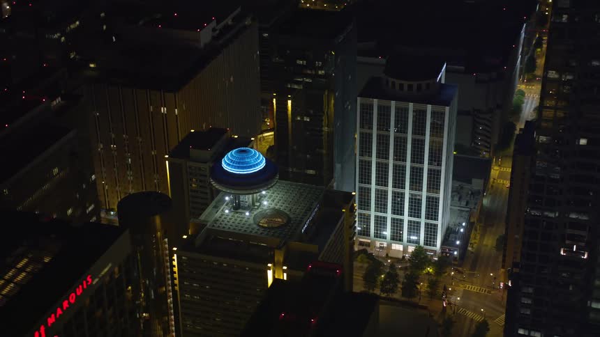Nighttime aerial footage of orbiting Hyatt Regency in Downtown Atlanta showcasing the citys skyline with vibrant lights on tall skyscrapers