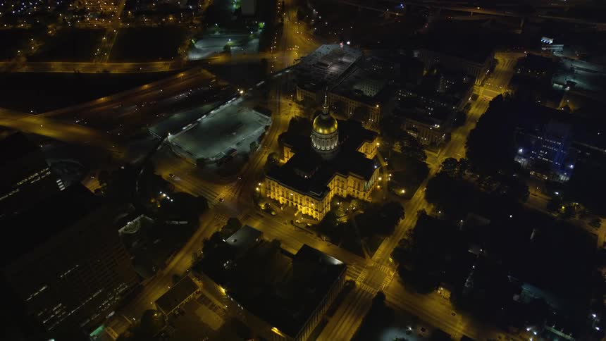 Aerial footage at night flying over Atlantas downtown area revealing the State Capitol building and skyscrapers towering over the city
