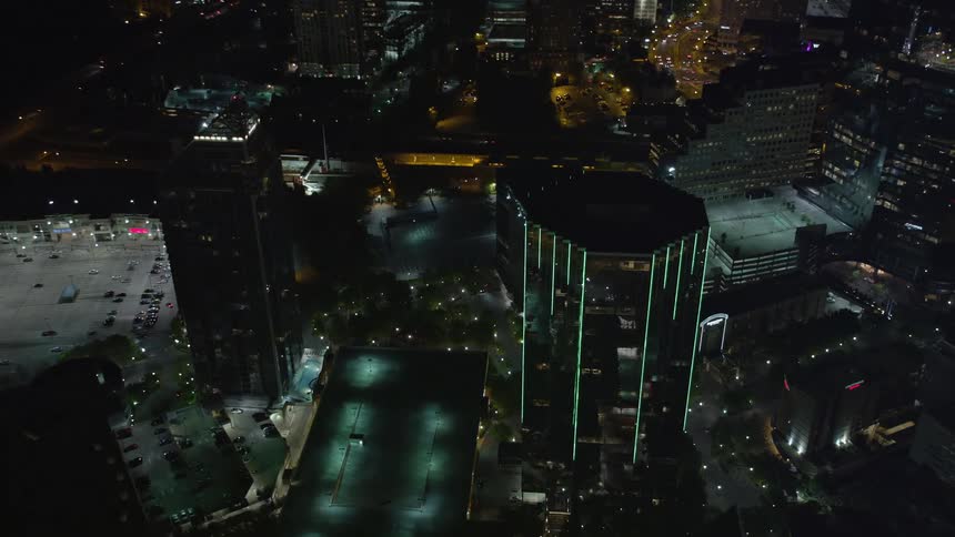 A aerial video clip of the high-rise building at 3340 Peachtree Road in Buckhead Georgia during nighttime features lit-up office buildings and a clear sky