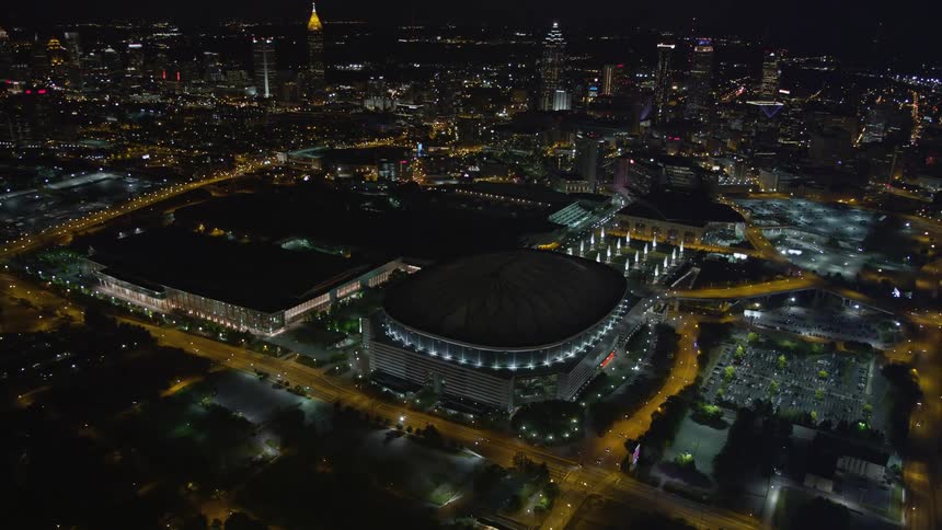 A night-time aerial view of the Georgia Dome in Atlanta revealing the downtown skyline as the camera flies away