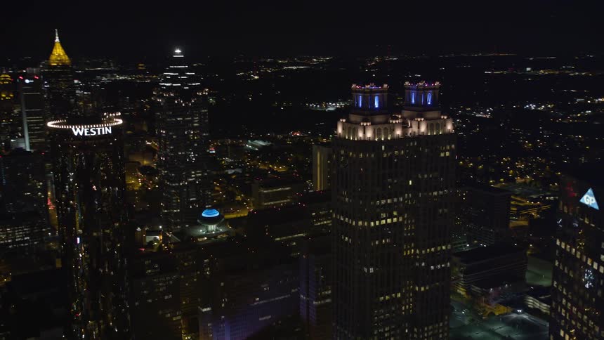 A aerial video orbits the tops of brightly lit skyscrapers in Downtown Atlanta Georgia during a clear summer night