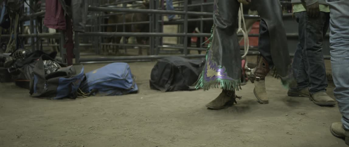 A bull rider spins wearing chaps