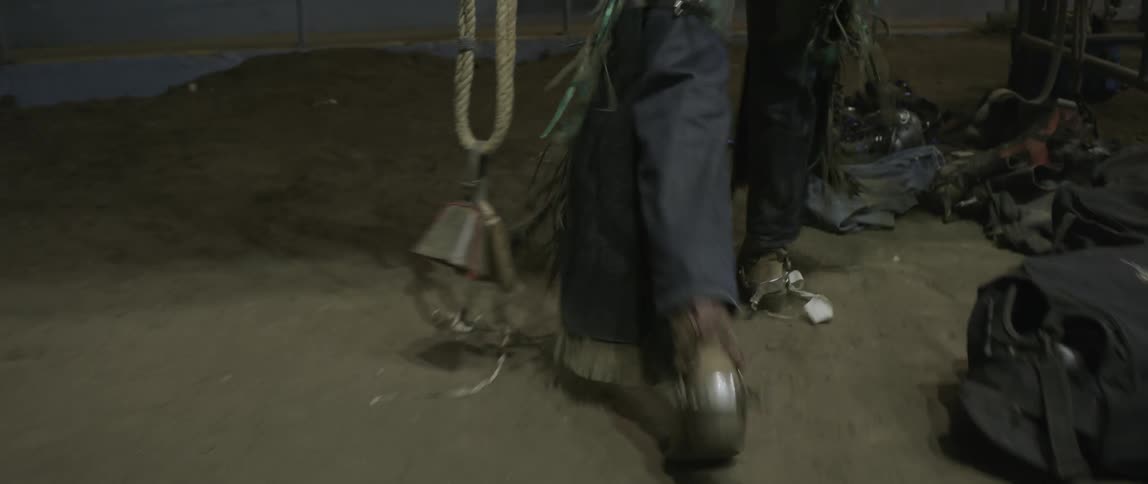 A rodeo bull rider carries a cowbell on a rope