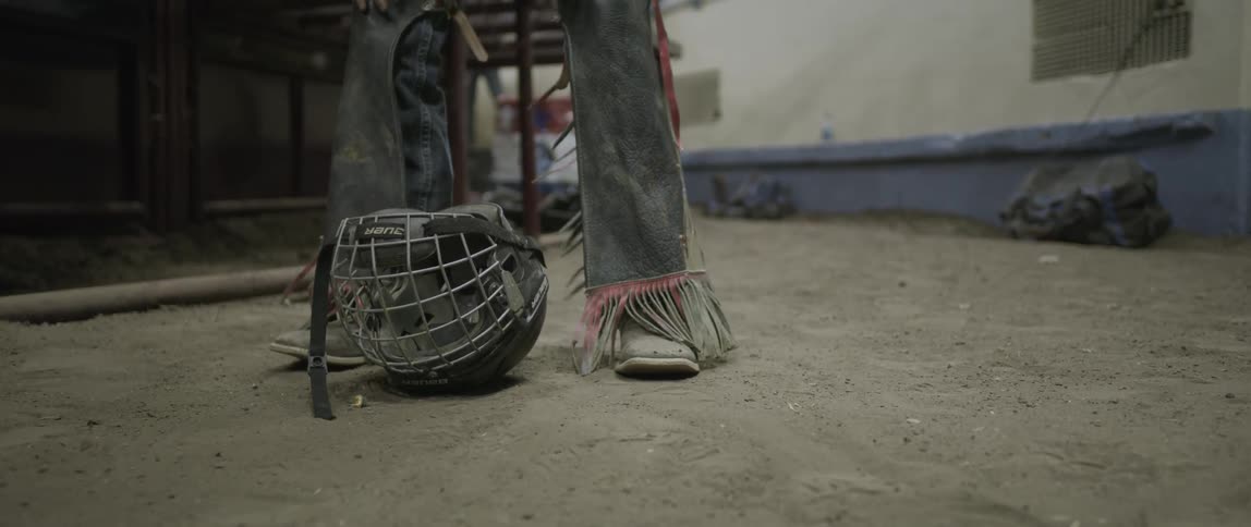 A bull rider picks up his helmet