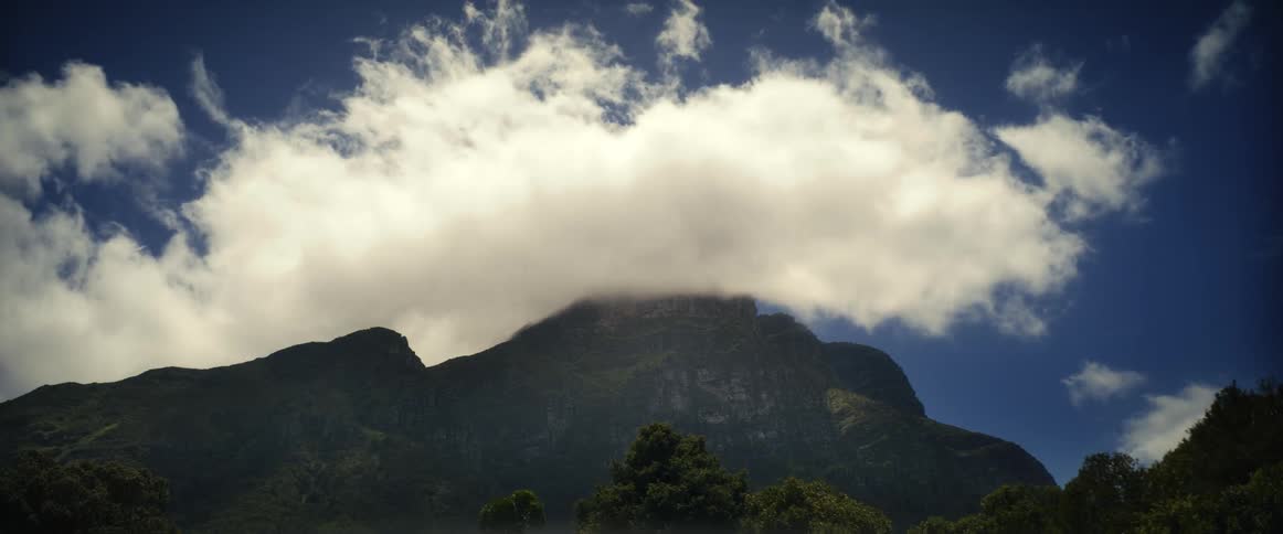 Clouds floating above a mountain peak in the daytime